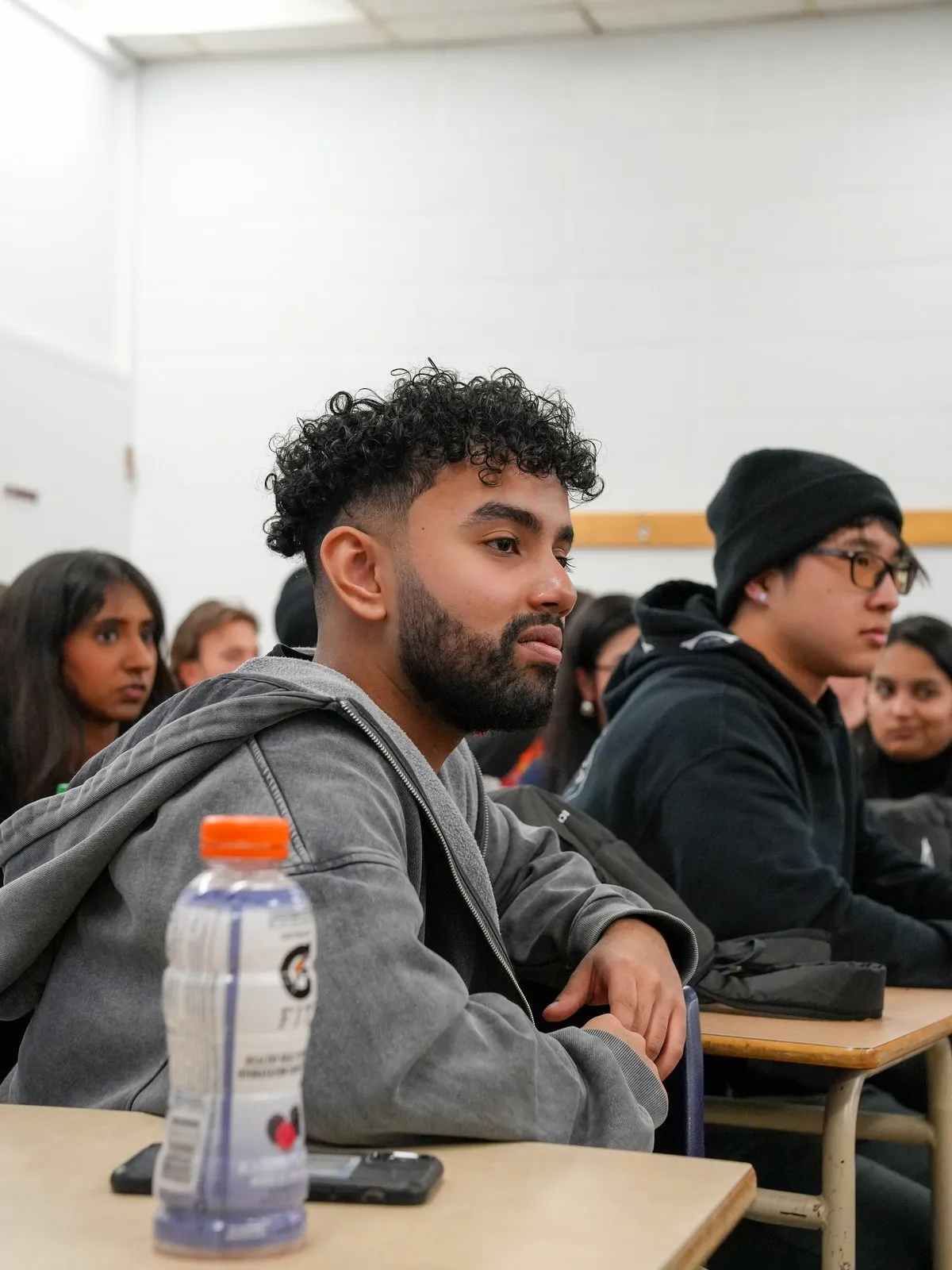 Students seated at classroom desks listen closely during a competition.